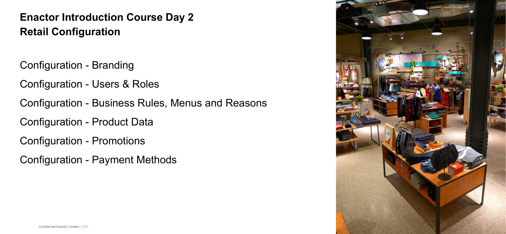 Daily Programme - Day 2 slide. Header bar: Daily Programme - Day 2 (dark background, white text). Enactor logo top right. Two bold lines: Enactor Introduction Course Day 2 and Retail Configuration. Six session topics listed below: Configuration - Branding. Configuration - Users &amp; Roles. Configuration - Business Rules, Menus and Reasons. Configuration - Product Data. Configuration - Promotions. Configuration - Payment Methods. Right side: photograph of a retail clothing store interior showing racks of hanging garments, shelving displays, and modern store fixtures with warm lighting. Footer: Confidential Enactor Limited | 2026.